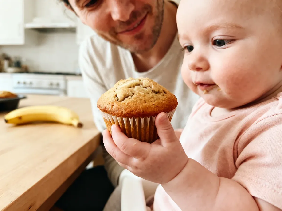 Niemowlę trzymające miękką domową muffinkę podczas nauki samodzielnego jedzenia